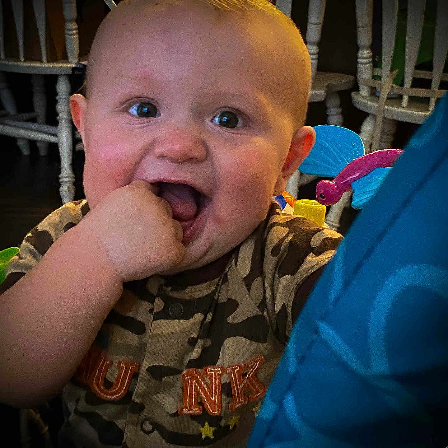 Asher is registered to the contest to win money with this photo: baby, bright_eyes, camo_clothing, chair, child, closeup, cute, face, fun, furniture, hand_in_mouth, happy, home, indoor, infant, person, playful, portrait, smiling, toy