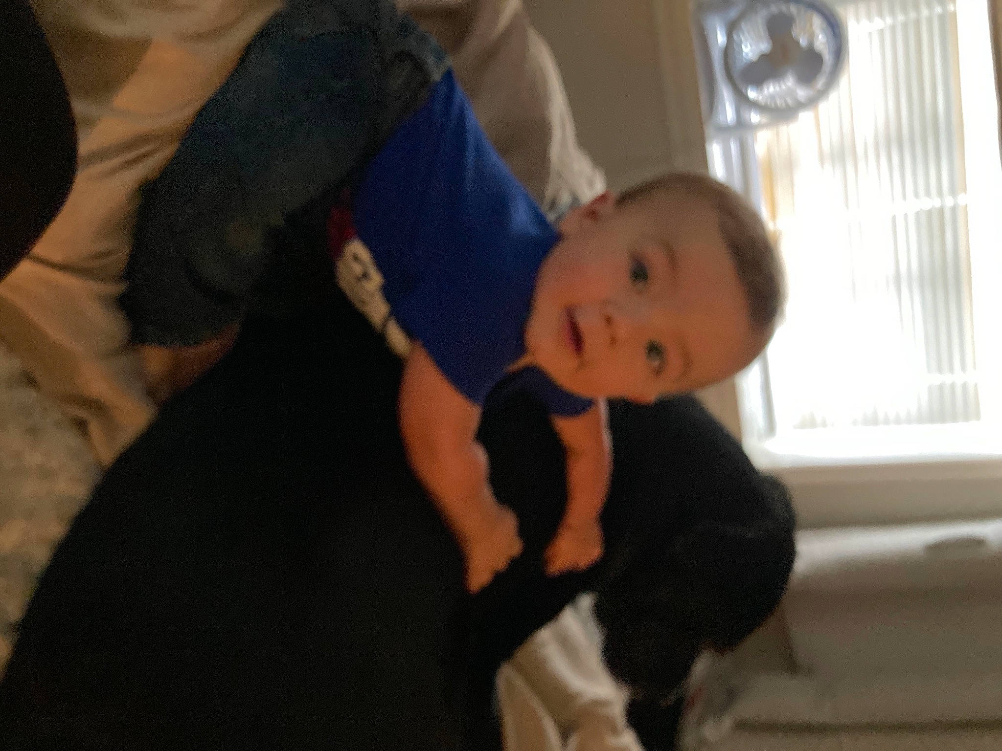 Paul is registered to the contest to win money with this photo: abdomen, baby, baby_toddler_clothing, child, comfort, curtain, elbow, flooring, fun, gesture, lap, person, room, sitting, smile, toddler, trunk, vertebrate, window, window_blind