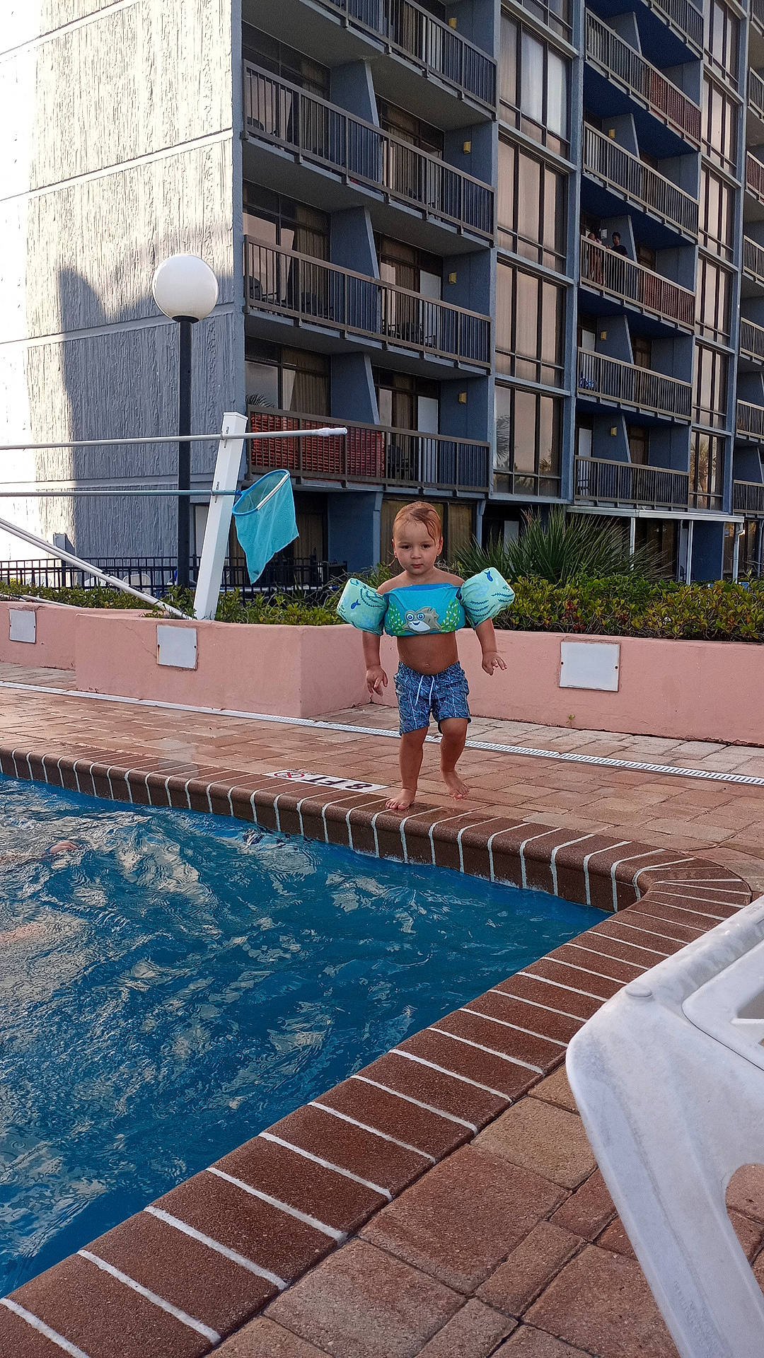 Greyson is registered to the contest to win money with this photo: aqua, barefoot, building, chair, composite_material, condominium, flooring, fun, house, leisure, outdoor_furniture, person, property, real_estate, recreation, shorts, smile, swimming_pool, thigh, water