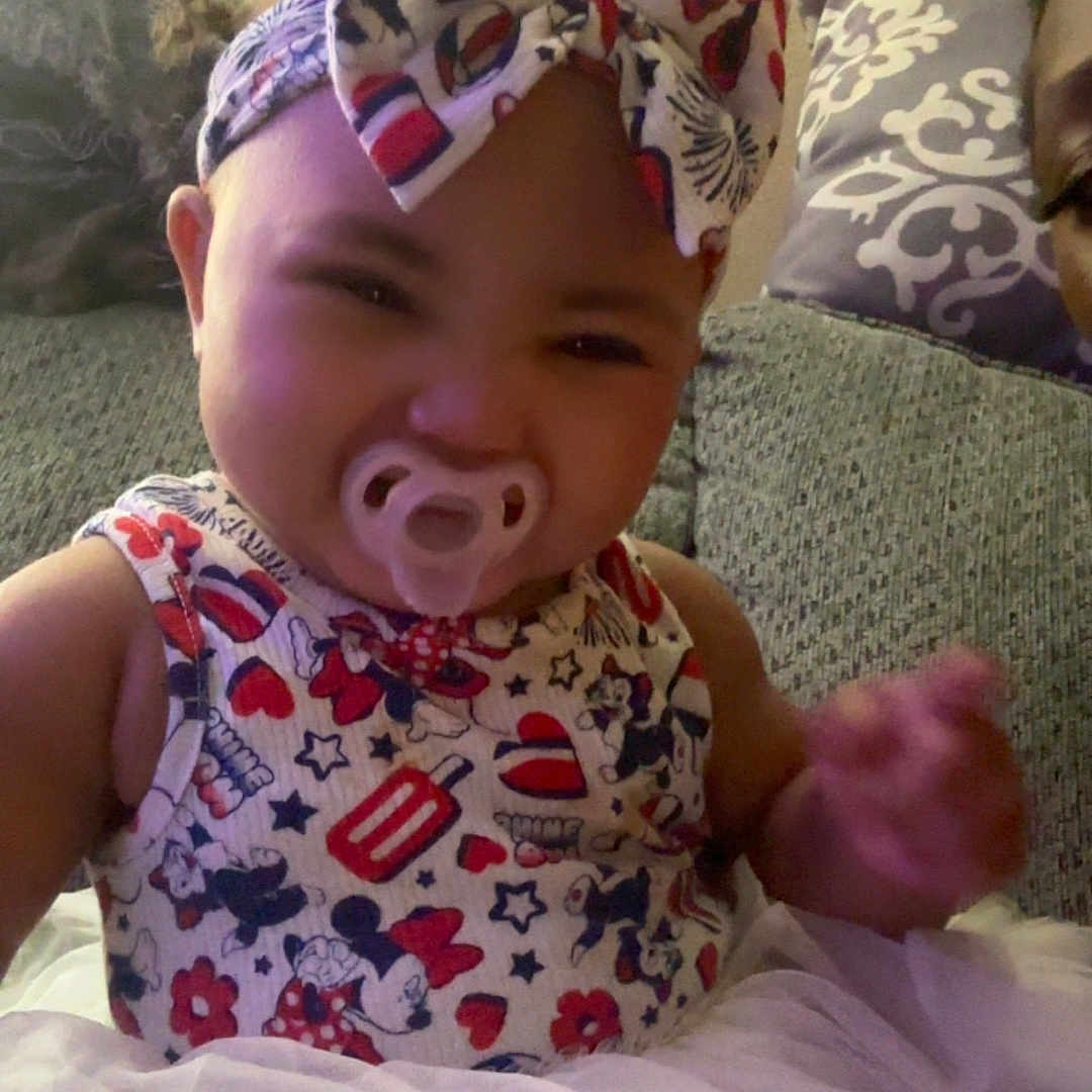 Renity joined the competition — help win amazing prizes! baby, child, couch, cute, dress, fabric, face, furniture, happy, headband, home, indoor, infant, pacifier, patterned_clothing, person, portrait, seated, smiling, toddler