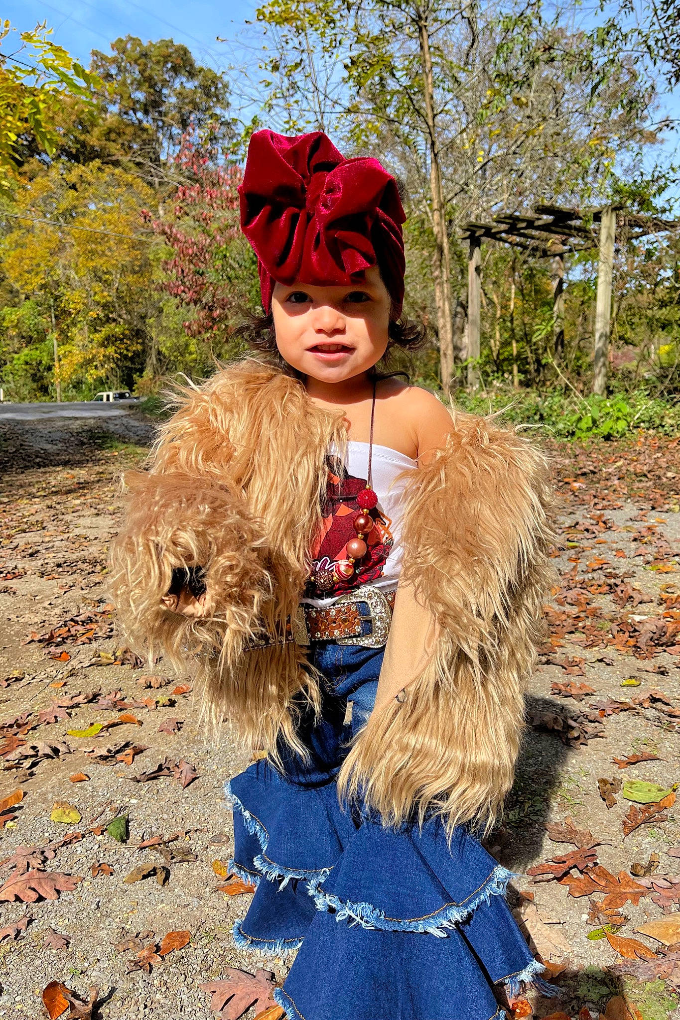 Esmeralda is registered to the contest to win money with this photo: costume, costume_design, electric_blue, feather, fur, fur_clothing, grass, headgear, headwear, jacket, landscape, natural_material, people_in_nature, person, plant, red, sky, street_fashion, toddler, tradition