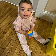 Cienna joined the competition — help win amazing prizes! toddler, child, baby, floor, wooden_floor, indoor, toy, ball, hoodie, pink_clothing, socks, person, curious, sitting, looking_up, yellow_furniture, casual_clothing, young_child, cute, home