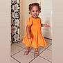 accessory, beads, braided_hair, child, curtain, cute, door, fashion, footwear, girl, happy, indoor, orange_dress, person, portrait, smiling, standing, tile_floor, toddler, young_child