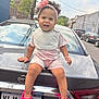Aubree joined the competition — help win amazing prizes! toddler, child, smiling, pink_headband, pink_crocs, car, nissan, license_plate, urban, street, sidewalk, buildings, daylight, clothing, shorts, bib, curly_hair, earrings, happy, outdoor