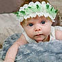 baby, flower_crown, blue_eyes, blanket, soft_texture, infant, cute, face, portrait, child, resting, close_up, skin, headwear, indoors, cozy, expression, young, adorable, sleepy