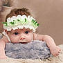baby, infant, flower_crown, blue_eyes, cute, lying_down, fluffy_cushion, soft_texture, skin, portrait, child, adorable, indoor, closeup, headwear, small_hands, curious, face, young_child, resting