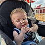 Maverick joined the competition — help win amazing prizes! baby, child, stroller, outdoor, sunlight, smile, happy, face, hands, clothing, blue_outfit, seatbelt, fairground, tent, sky, clouds, playful, infant, closeup, person