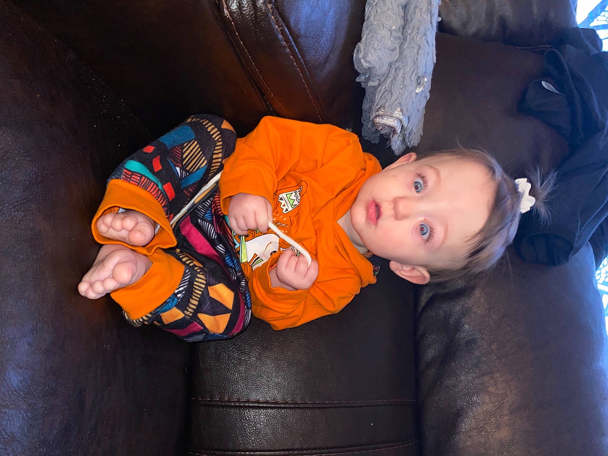 Serena is registered to the contest to win money with this photo: baby, baby_products, baby_toddler_clothing, child, comfort, electric_blue, fun, hat, mammal, mouth, orange, person, personal_protective_equipment, room, sitting, surprise, toddler, toy, vertebrate