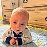 baby, child, infant, quilt, blue, yellow, stars, moon, floor, wooden_dresser, furniture, face, eyes, clothing, long_sleeves, crawling, indoors, cute, portrait, curious