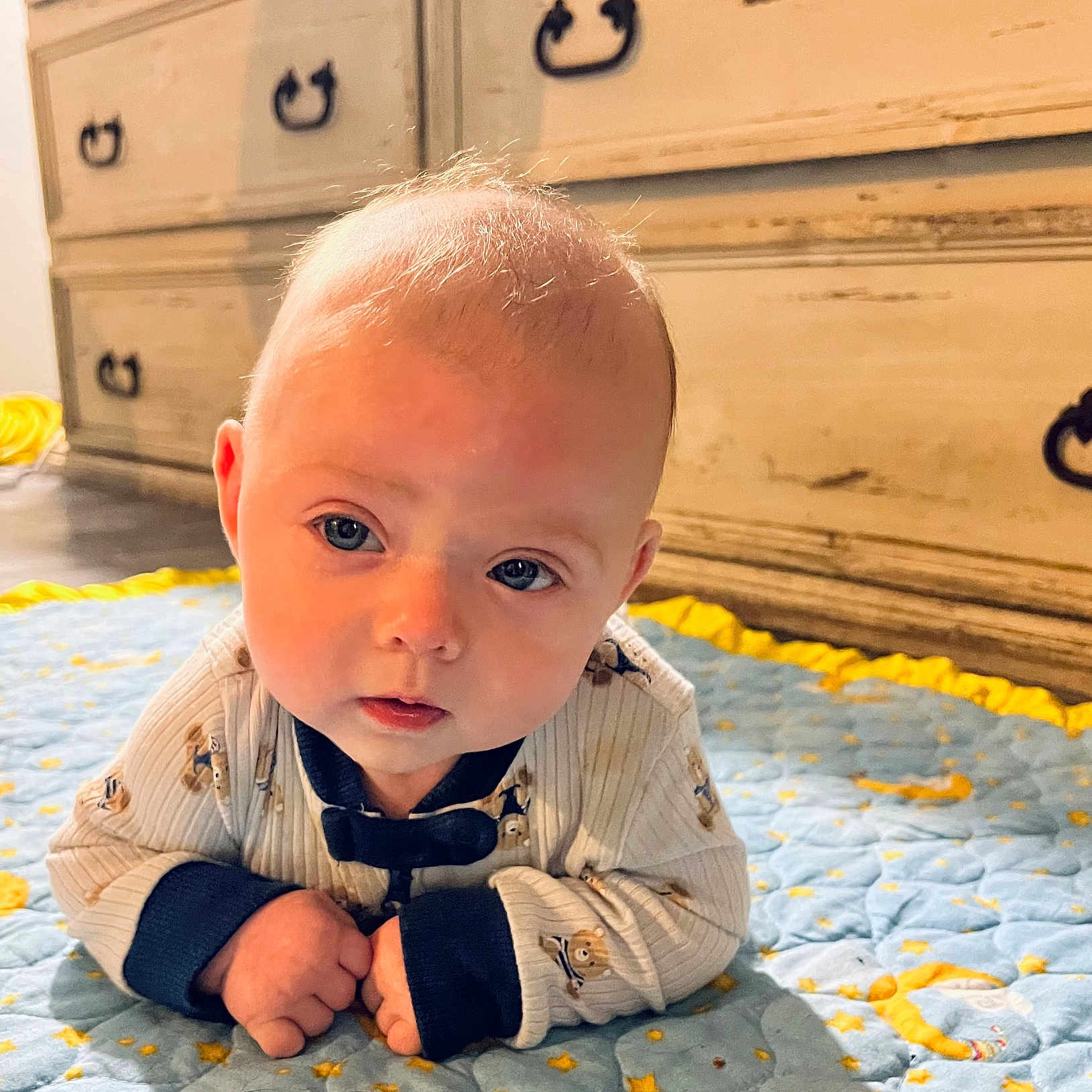 Lachlan joined the competition — help win amazing prizes! baby, child, infant, quilt, blue, yellow, stars, moon, floor, wooden_dresser, furniture, face, eyes, clothing, long_sleeves, crawling, indoors, cute, portrait, curious
