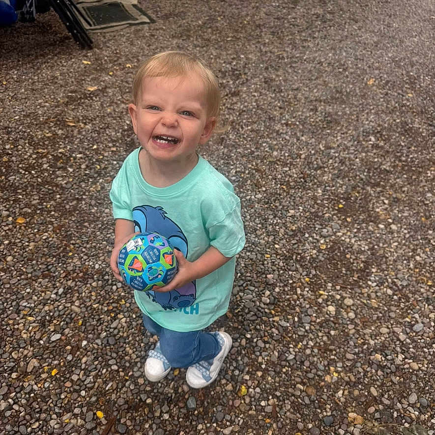 Amirah is registered to the contest to win money with this photo: toddler, child, smiling, ball, outdoor, gravel, casual, happy, playing, toy, person, young, clothing, sneakers, standing, daylight, fun, cute, light, portrait