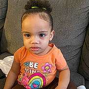 Nevaeh joined the competition — help win amazing prizes! brown_pants, casual_clothing, child, colorful_graphics, couch, curly_hair, cute, furniture, girl, hair_tie, home, indoor, orange_shirt, person, portrait, serious_expression, sitting, sofa, toddler, young_child