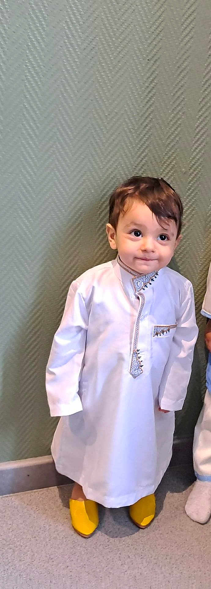 Anes a rejoint le concours — aidez-le/la à gagner de superbes lots ! boy, carpet, child, cute, eyes, face, feet, hair, indoor, innocence, person, photography, portrait, smile, standing, toddler, traditional_clothing, wallpaper, white_robes, yellow_shoes