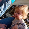 toddler, child, smile, blonde_hair, jeans, blue_shirt, tattoo, hand, outdoor, porch, sunlight, person, clothing, baby, face, expression, holding, casual, wood_siding, daylight
