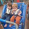 toddler, child, shopping_cart, blue_cart, store, clothing, price_tags, barefoot, curious, straps, seated, indoor, floor, retail, shopping, cute, casual_clothing, two_children, young, portrait