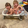 toddler, baby, child, bathtub, indoor, floor, smile, curly_hair, diaper, plastic_tub, playtime, happy, sitting, two_children, household_items, water_bottle, toy, floor_tiles, wall, bathroom