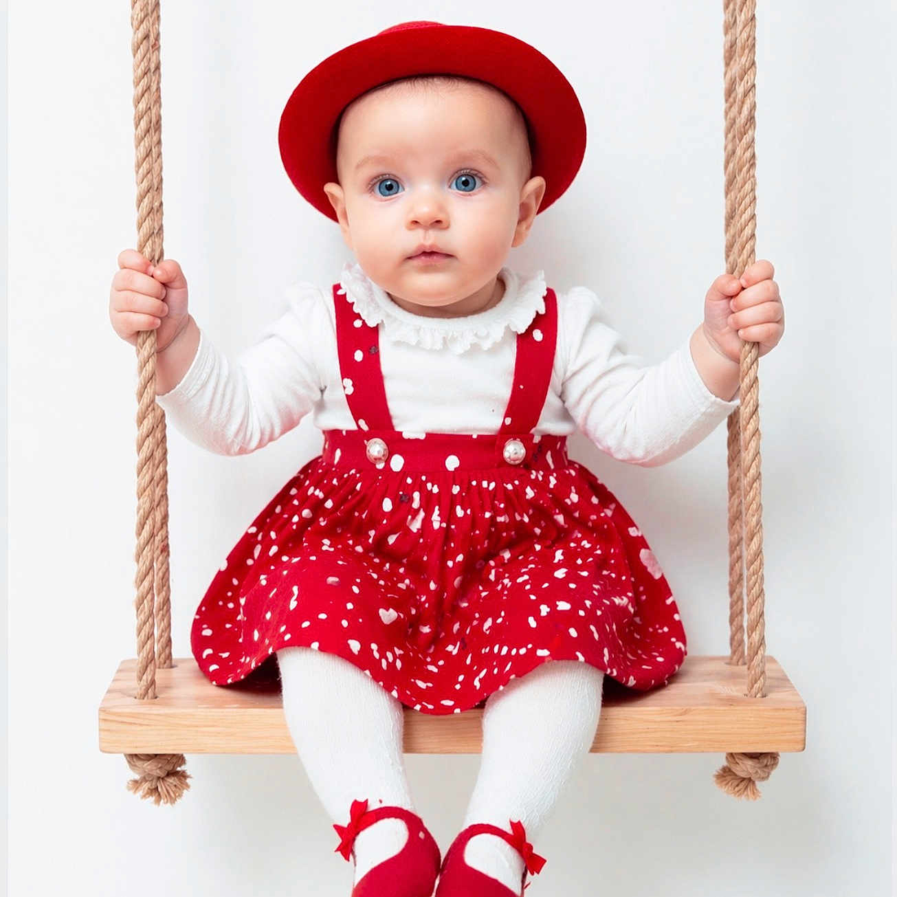 Mila a rejoint le concours — aidez-le/la à gagner de superbes lots ! baby, child, swing, red_hat, red_dress, white_tights, red_shoes, rope, wooden_swing, blue_eyes, indoor, portrait, cute, childrens_fashion, sitting, holding, studio, white_background, expression, innocence