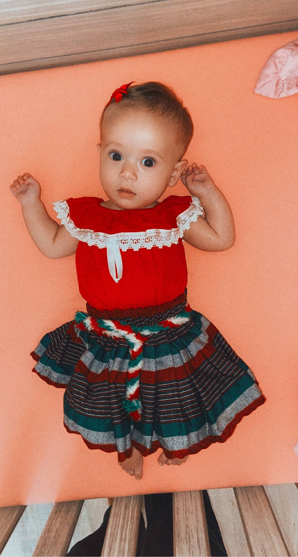 Ariella is registered to the contest to win money with this photo: abdomen, baby, baby_toddler_clothing, cheek, child, day_dress, dress, face, magenta, one_piece_garment, pattern, person, pink, product, red, skin, sleeve, sock, toddler, trunk