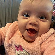 Rosaline is registered to the contest to win money with this photo: baby, smiling, close_up, pink_sweater, child, cute, happy, indoor, portrait, face, infant, apparel, cozy, warm, young_child, person, expression, cheerful, cute_animal_design, joyful