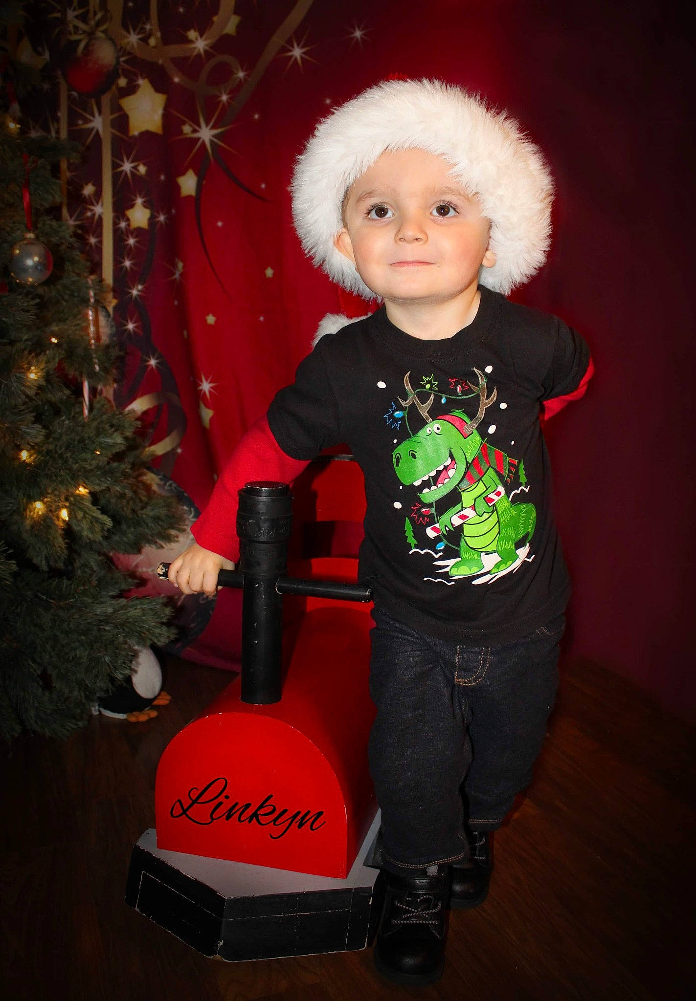 Linkyn is registered to the contest to win money with this photo: baby_toddler_clothing, carmine, child_model, christmas, christmas_decoration, christmas_eve, christmas_ornament, christmas_tree, conifer, costume_accessory, costume_hat, fictional_character, fur, fur_clothing, headwear, holiday, holiday_ornament, interior_design, ornament, person