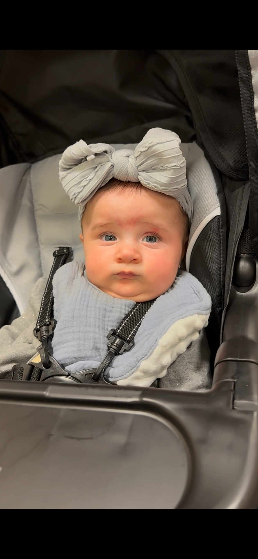Layaal is registered to the contest to win money with this photo: baby, child, stroller, headband, bow, face, blue_eyes, clothing, straps, infant, cute, portrait, people, sitting, indoors, expression, closeup, soft_lighting, baby_bib, seat