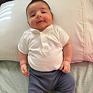 Hamed joined the competition — help win amazing prizes! baby, infant, child, pillow, bed, clothing, white_shirt, blue_pants, lying_down, indoors, cute, smiling, face, skin, head, hand, human, portrait, soft_light, cozy