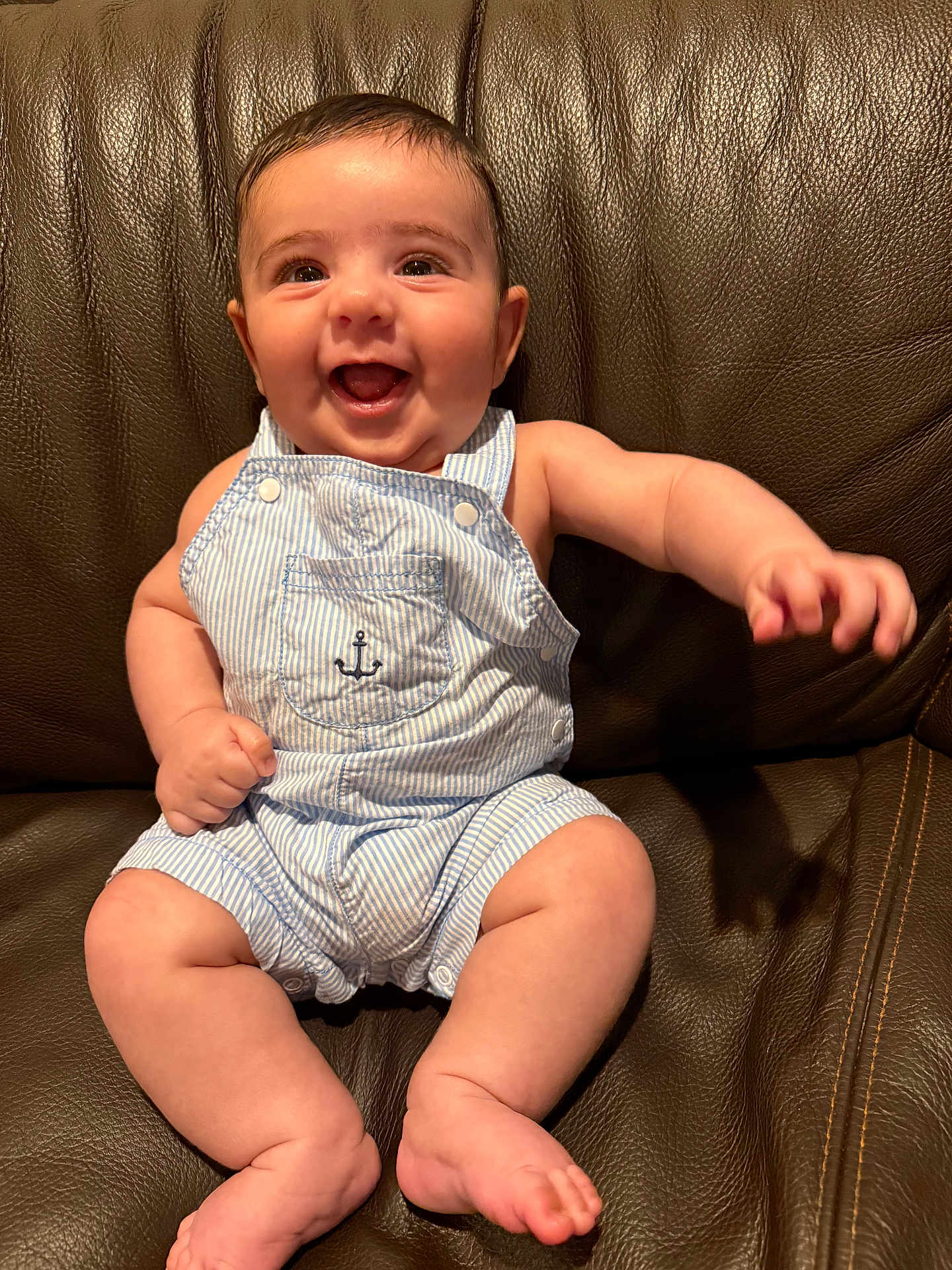 Hamed is registered to the contest to win money with this photo: baby, smiling, overalls, striped_clothing, infant, happy, sitting, leather_couch, cute, child, portrait, indoor, skin, one_person, young_child, small_hands, barefoot, bright_eyes, cheerful, casual_clothing