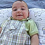 baby, smiling, child, plaid_overalls, green_shirt, pillow, elephant_pattern, outdoor, grass, cute, face, infant, portrait, happy, lying_down, young_child, clothing, baby_boy, background, soft