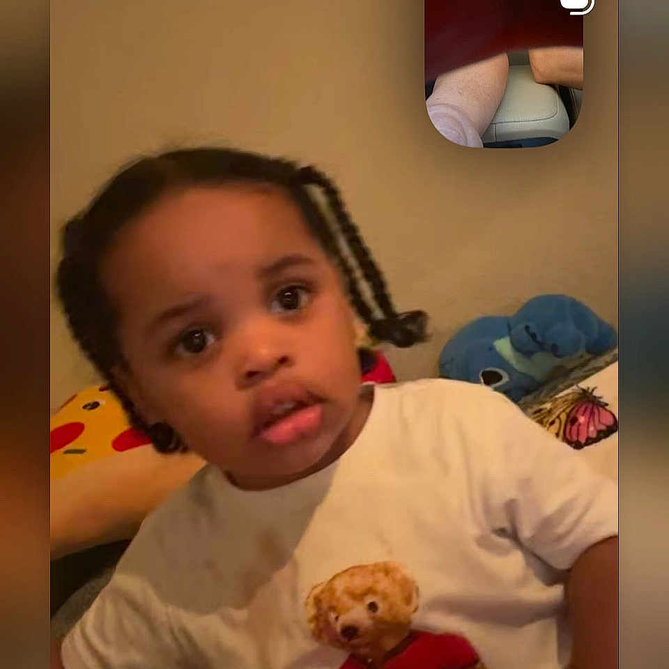 Tevari joined the competition — help win amazing prizes! toddler, child, braided_hair, white_shirt, teddy_bear, plush_toy, cushion, indoor, video_call, face, expression, person, young_child, colorful, cozy, furniture, seated, portrait, casual, home