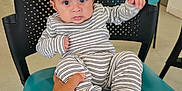 Jahan is registered to the contest to win money with this photo: baby, background, black_chair, casual_clothing, chair, child, curious, expression, floor, hand, indoor, infant, person, room, seated, striped_clothing, supporting_hand, teal_chair, toes, wide_eyes