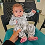 baby, background, black_chair, casual_clothing, chair, child, curious, expression, floor, hand, indoor, infant, person, room, seated, striped_clothing, supporting_hand, teal_chair, toes, wide_eyes