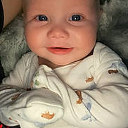 River is registered to the contest to win money with this photo: baby, infant, smiling, blue_eyes, onesie, animal_print, close_up, cute, cozy, blanket, child, face, portrait, happy, skin, young, person, indoor, soft, comfort