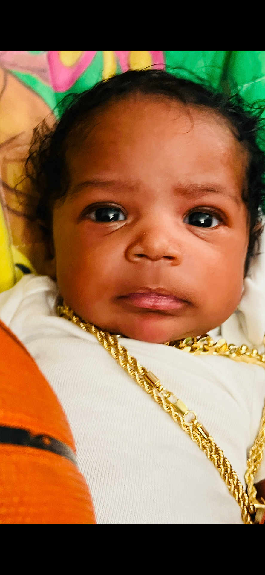 Selahsynai joined the competition — help win amazing prizes! baby, close_up, face, gold_chain, jewelry, white_clothing, curly_hair, portrait, infant, child, cute, looking_at_camera, colorful_background, soft_lighting, indoors, skin, expression, young, person, headshot