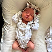 Parker is registered to the contest to win money with this photo: newborn, baby, sleeping, headband, onesie, infant, cute, cozy, cushion, blanket, soft, peaceful, resting, indoors, child, portrait, clothing, human, lying_down, adorable