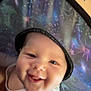 baby, smile, face, hat, indoor, child, joyful, portrait, person, cute, infant, headwear, white_clothing, expression, closeup, wall_photos, happy, young_child, small_person, cheerful