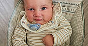 Ezekiel joined the competition — help win amazing prizes! baby, infant, pacifier, blanket, striped_clothing, bib, cushion, baby_chair, face, person, child, indoors, seated, cute, young, skin, hand, expression, comfort, fabric