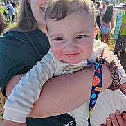 Ezekiel joined the competition — help win amazing prizes! adult, arms, baby, caregiver, child, crowd, daylight, event, family, grass, holding, infant, outdoor, pacifier, park, portrait, smiling, sunny, umbrella, wristband