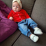 Victoria a rejoint le concours — aidez-le/la à gagner de superbes lots ! baby, blue_jeans, bow, casual, child, clothing, couch, cozy, footwear, gray_couch, headband, indoors, infant, person, portrait, purple_blanket, red_cardigan, relaxing, seated, white_shoes