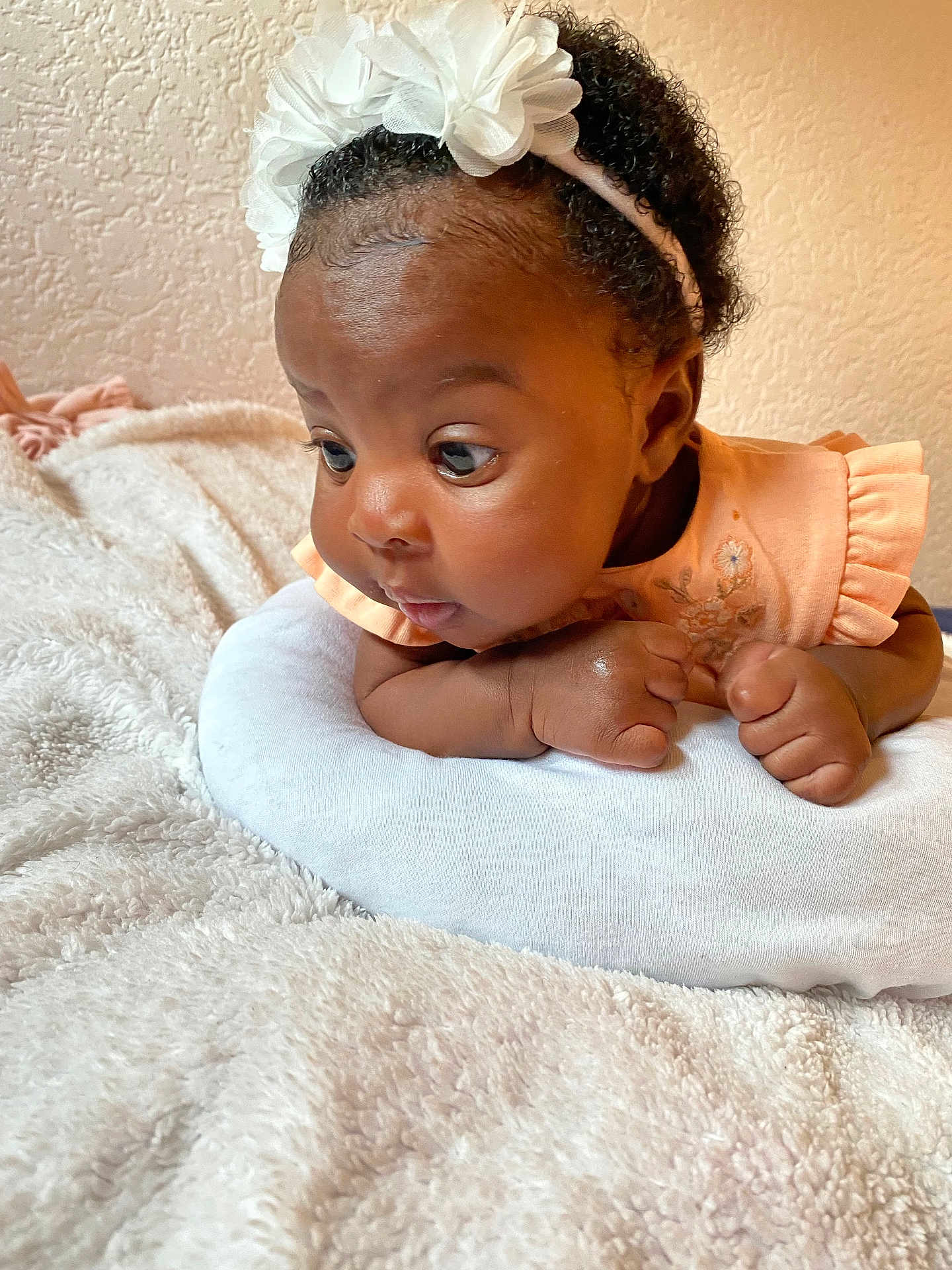 K.ferraz a rejoint le concours — aidez-le/la à gagner de superbes lots ! baby, infant, child, girl, headband, flower, peach_dress, pillow, blanket, curious, indoors, soft_texture, skin, face, hands, closeup, portrait, cute, lying_down, resting