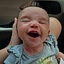 Milani is registered to the contest to win money with this photo: baby, child, smiling, happy, infant, clothing, grey_shirt, text_on_clothing, hand, car_interior, seat, person, cute, joyful, laughter, skin, head, face, human, sitting