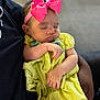 baby, sleeping, pink_bow, yellow_dress, infant, child, arm, hand, adult, holding, closeup, portrait, soft_light, indoor, cute, peaceful, tender, clothing, headband, person