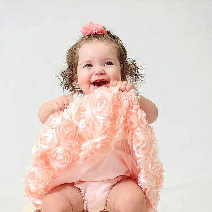 Shannon is registered to the contest to win money with this photo: baby, blanket, child, clothing, curly_hair, cute, fabric, flower, hands, happy, headband, infant, innocence, pink, portrait, sitting, smiling, soft, studio, toddler