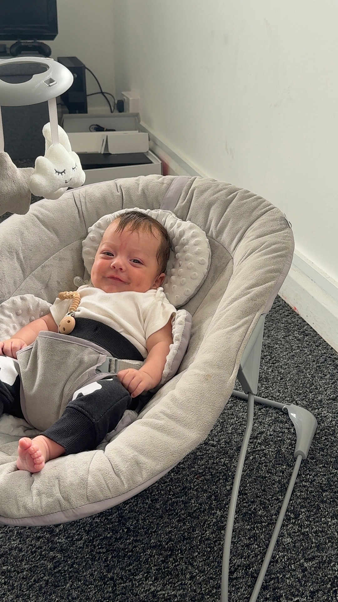 Noah is registered to the contest to win money with this photo: baby, infant, smile, baby_rocker, plush_toy, gray, carpet, indoor, child, cute, comfort, soft, clothing, person, young, relaxing, toy, smiling, head, seat