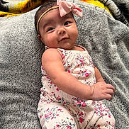 Cataleya is registered to the contest to win money with this photo: baby, infant, child, pink_bow, headband, floral_outfit, blanket, gray_blanket, soft_texture, cute, portrait, indoors, smiling, happy, skin, face, arm, hand, lying_down, cozy
