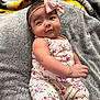 baby, infant, child, pink_bow, headband, floral_outfit, blanket, gray_blanket, soft_texture, cute, portrait, indoors, smiling, happy, skin, face, arm, hand, lying_down, cozy