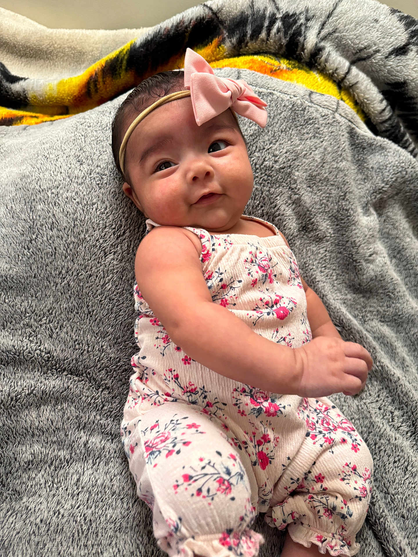 Cataleya is registered to the contest to win money with this photo: baby, infant, child, pink_bow, headband, floral_outfit, blanket, gray_blanket, soft_texture, cute, portrait, indoors, smiling, happy, skin, face, arm, hand, lying_down, cozy