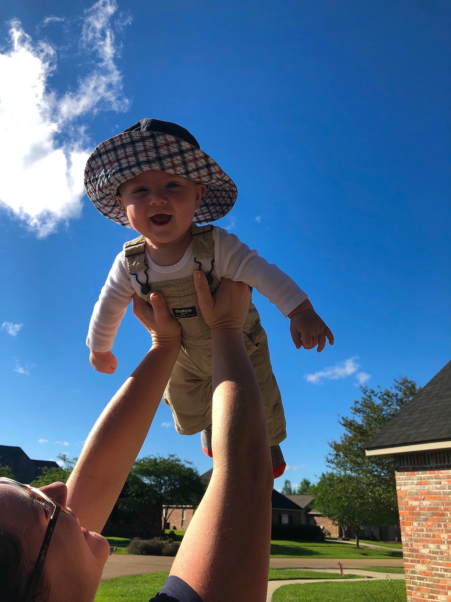 Watson is registered to the contest to win money with this photo: arm, child, cloud, finger, fun, grass, hand, headgear, headwear, human_body, leg, male, person, photography, play, public_space, sky, summer, sunlight, toddler