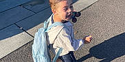 Jaxson joined the competition — help win amazing prizes! child, boy, backpack, toy, outdoor, sidewalk, sunlight, shadow, happy, casual_clothing, shorts, sneakers, playful, daylight, pavement, concrete_wall, expression, walking, small_toy_car, urban