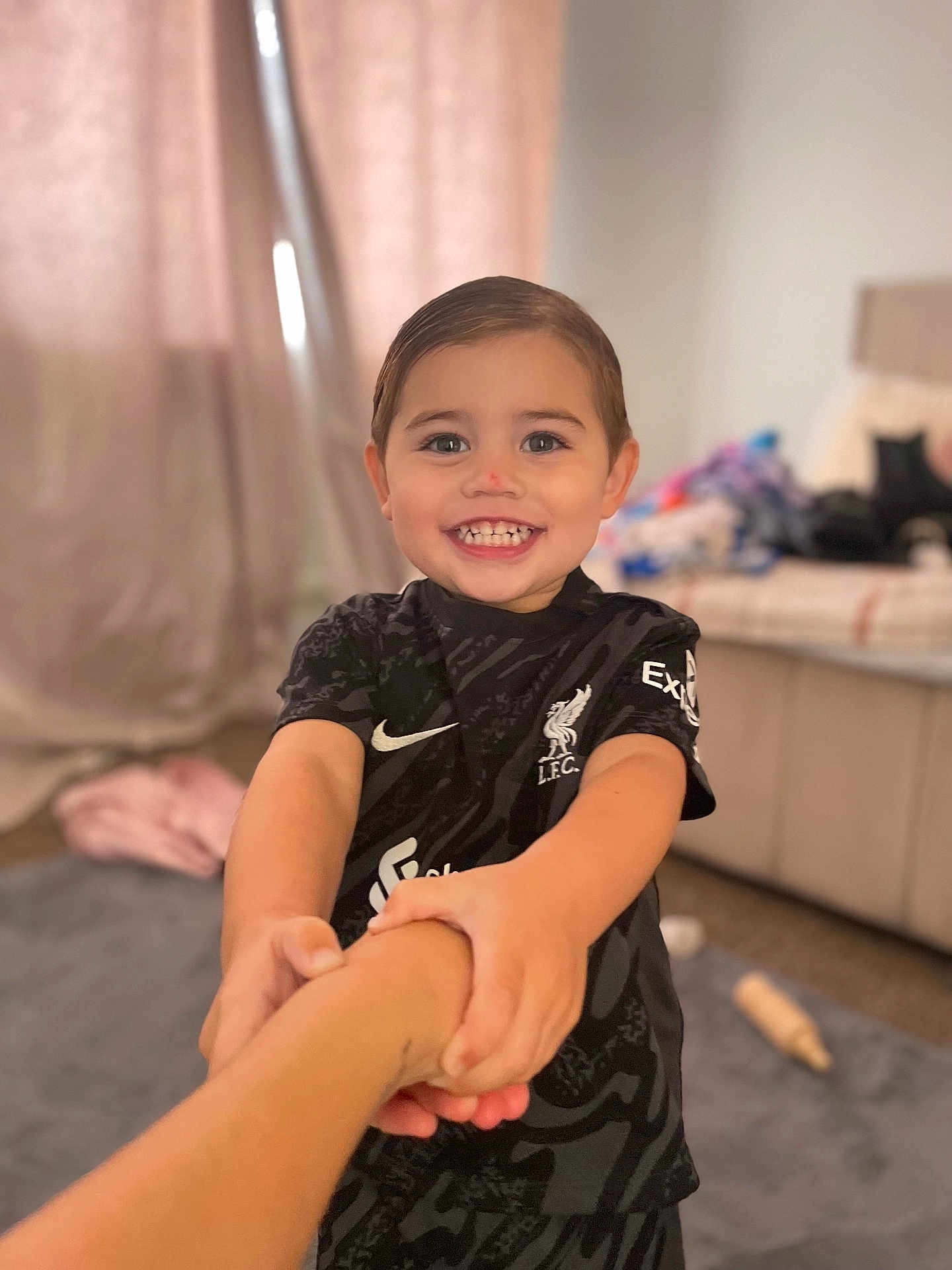 Jaxson is registered to the contest to win money with this photo: child, smiling, holding_hands, indoor, person, black_clothing, short_hair, happy, portrait, young_child, blurred_background, carpet, bedroom, curtains, furniture, home, casual, close_up, cheerful, joyful