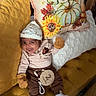 baby, infant, couch, pillow, pumpkin, sunflower, hat, mittens, socks, wooden_sign, 2_months, smiling, tufted_couch, yellow, brown_clothing, striped_shirt, cozy, indoor, carpet, person